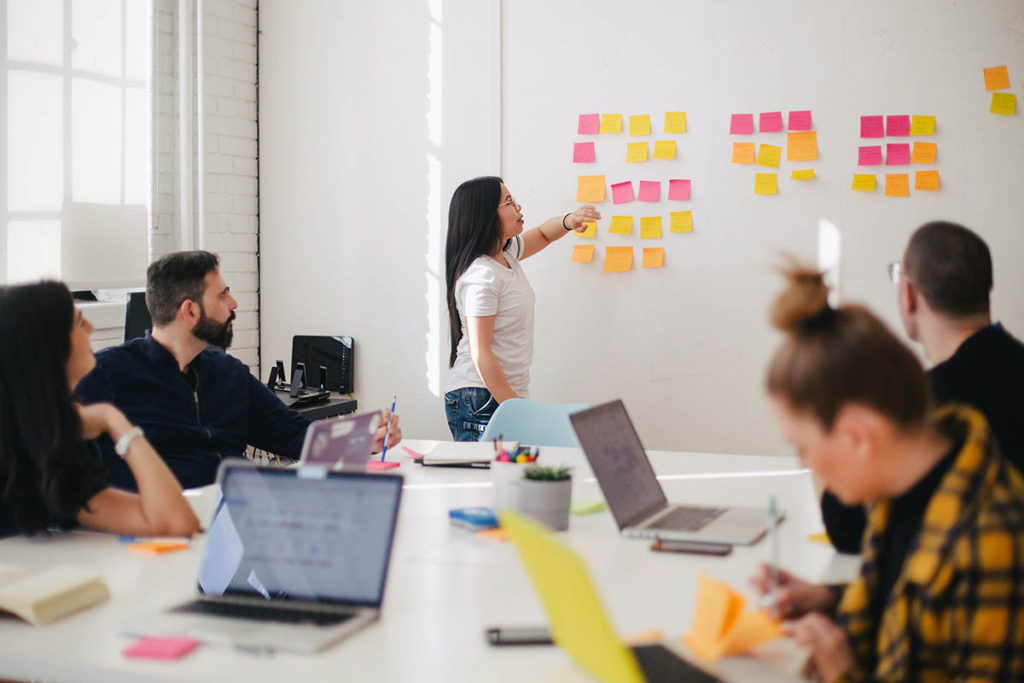 A group of people complete a brainstorming exercise using bright colored sticky notes.