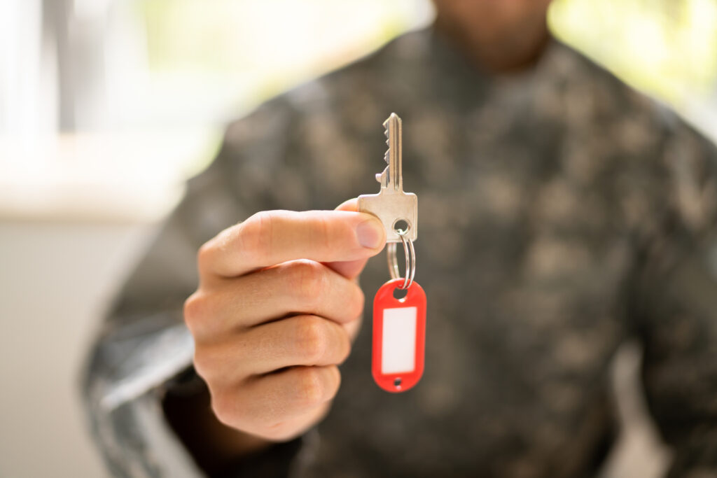 The hand of an individual in camouflage holding a house key.